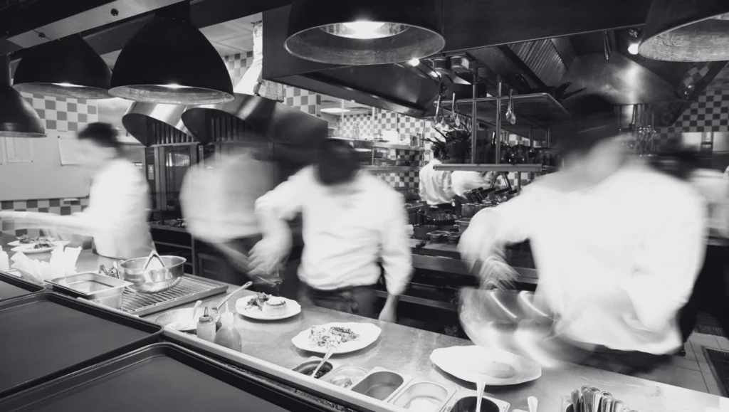Chefs working in a busy restaurant kitchen. เชฟกำลังทำงานในครัวร้านอาหารที่วุ่นวาย