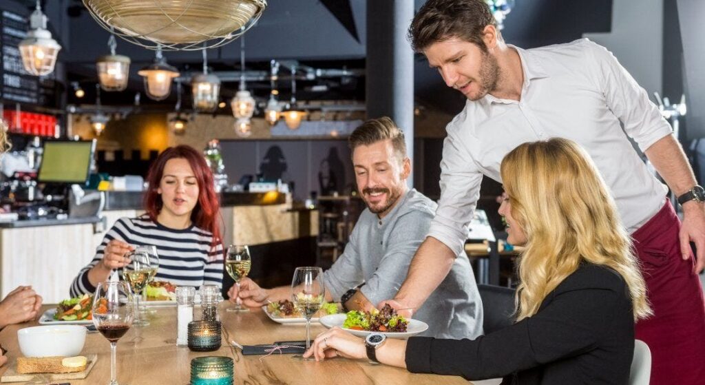 Diners being served at a restaurant table. ลูกค้ากำลังได้รับการเสิร์ฟที่โต๊ะอาหาร