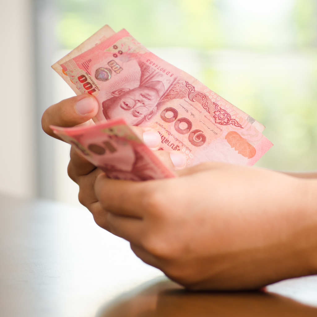 Hands holding Thai baht banknotes. มือถือธนบัตรเงินบาทไทย