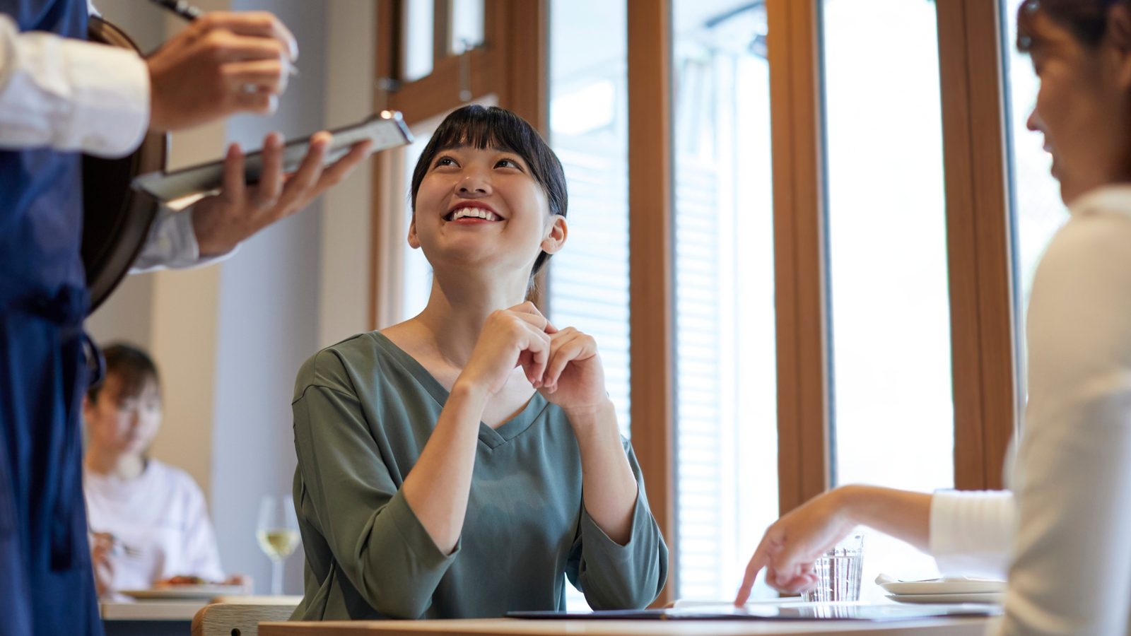 A happy guest smiling while ordering, the payoff of being the restaurant an AI recommends. ลูกค้ายิ้มอย่างมีความสุขขณะสั่งอาหาร ผลลัพธ์ของการเป็นร้านที่ AI แนะนำ
